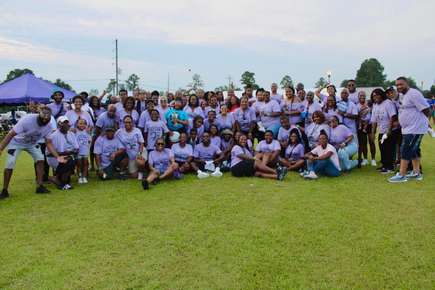 Large family in matching lavender Cousins Day shirts gathered together on the field