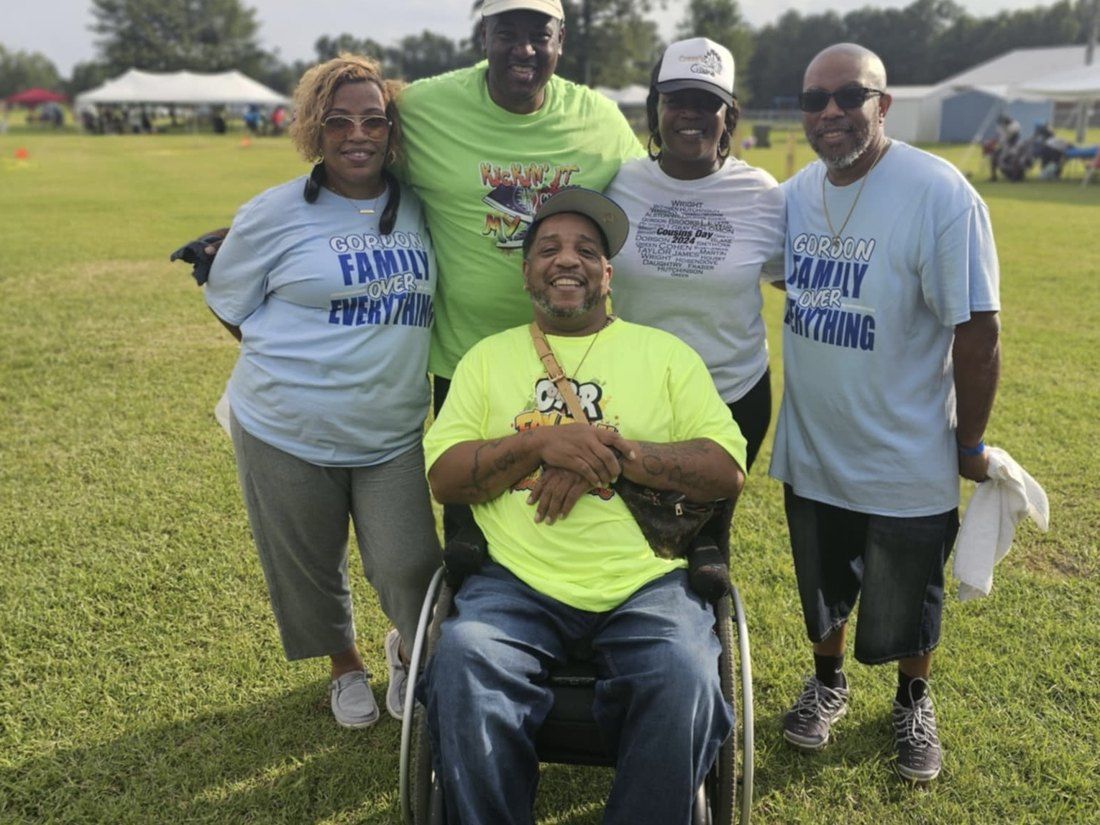 Family members smiling together, including a relative in a wheelchair, at Cousins Day